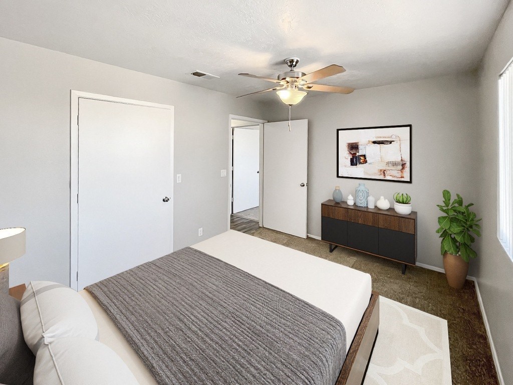 A bedroom with a bed, a bench, and a ceiling fan.
